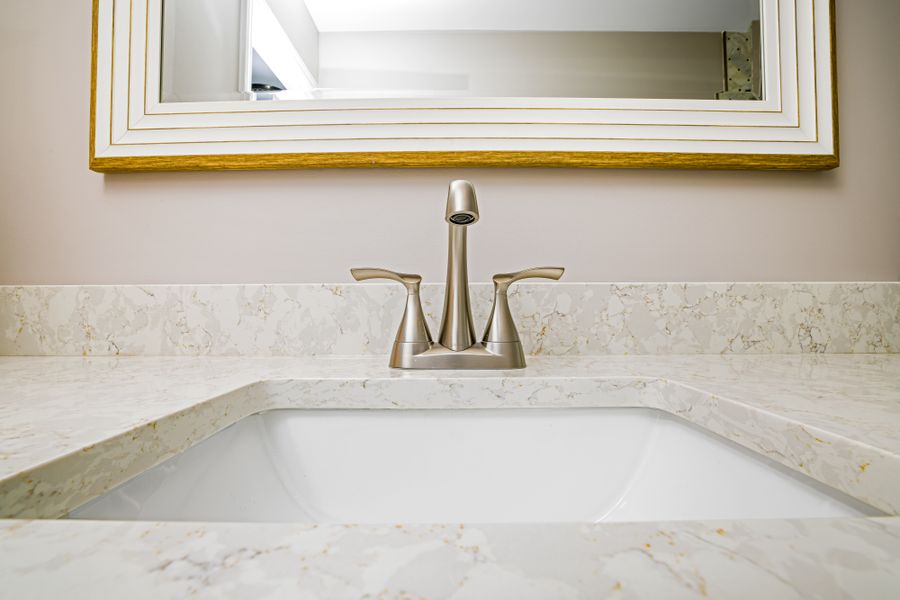 A brushed nickel bathroom faucet over a white sink